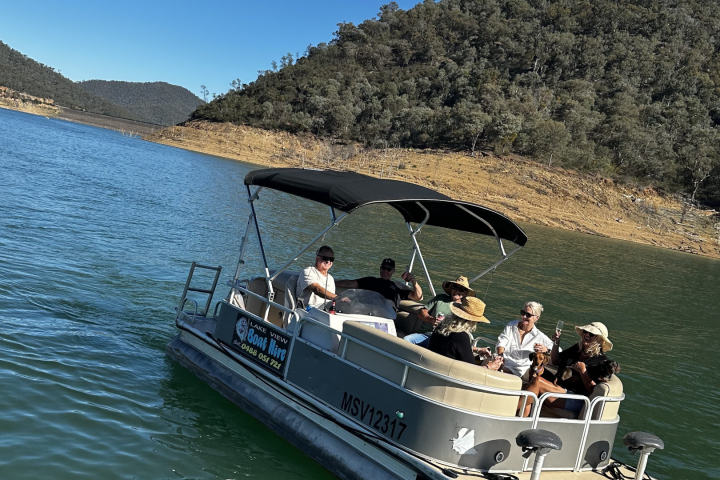 Group on a pontoon boat on a scenic lake with forested hills.