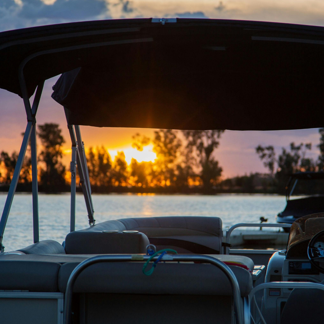 Silhouette of a boat against a sunset over a lake.